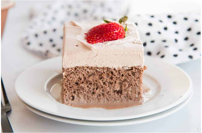 chocolate tres leches cake with cocoa and whipped cream.