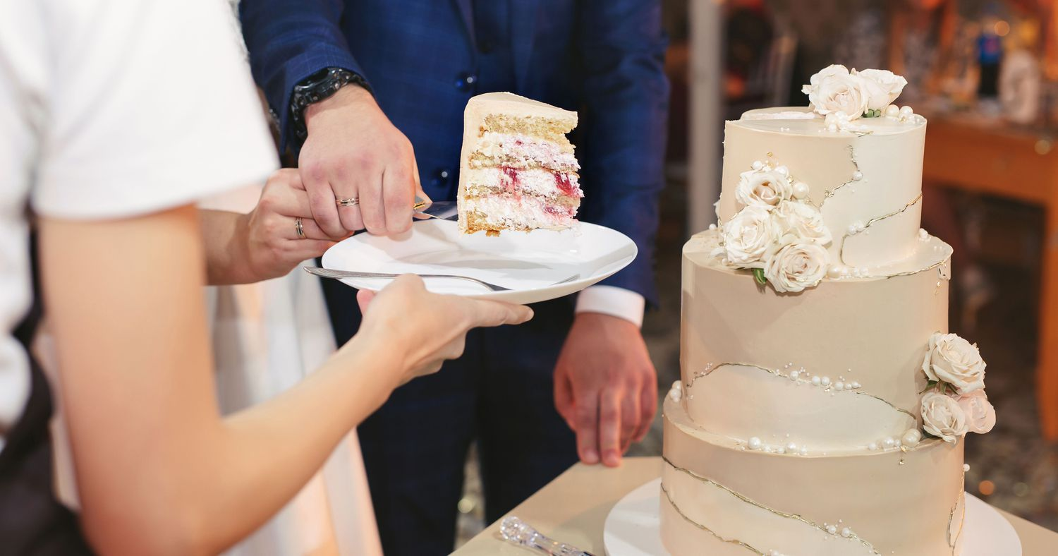 A newlywed couple cutting a slice of wedding cake.